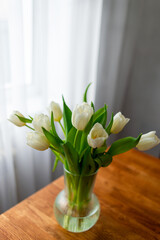 Bouquet of white tulips in a glass vase on the table