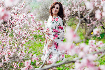 a woman stands in a garden of flowering pink trees nature park spring