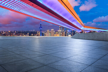 Empty square floor and pedestrian bridge with city skyline at night in Shanghai, China.
