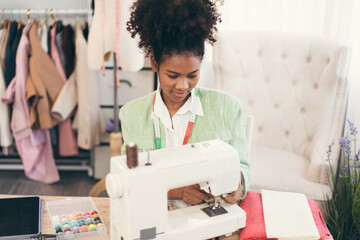 Happy beautiful African American woman fashion designer clothes working with sewing in own dressmaking studio or boutique	