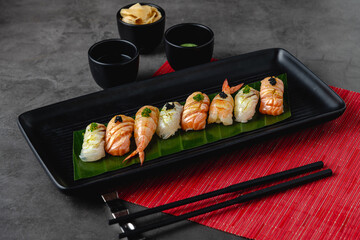 Sushi set of various products on a black stone plate