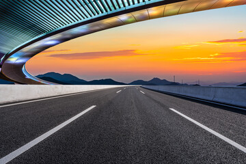 Asphalt road and Bridge with mountain background at sunset