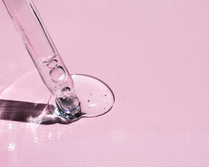 Natural rose bud in a drop of moisturizing essence on a pink background. Natural cosmetic. 