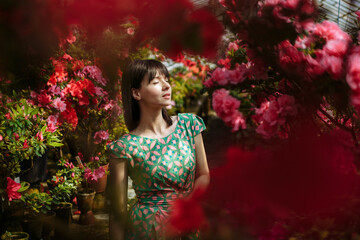 Obraz na płótnie Canvas Beautiful girl in a green dress in a garden of blooming azaleas