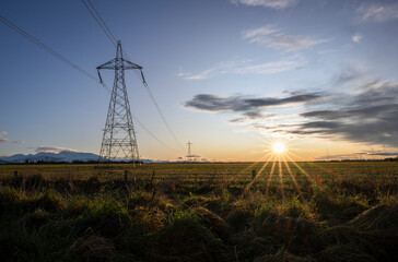 High voltage power pylon towers and powerlines at sunrise, Canterbury, South Island
