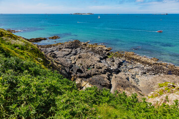 beautiful view from the island towards the sea, small islets and a green slope, Saint Malo, France