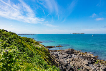 beautiful view from the island towards the sea, small islets and a green slope, Saint Malo, France