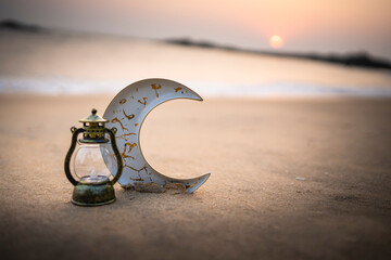 Vintage lamp and crescent moon in a sea background, Ramadan and Eid concept Sunset Selective focus