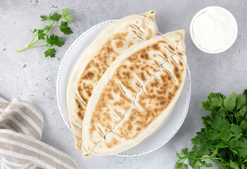  Qutab with green and sour cream or yogurt on gray background. Azerbaijani flat bread with greens. Top view, copy space. Azerbaijani, armenian food