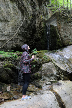 Side view of woman standing on rock in forest