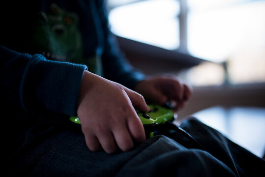 Midsection of boy playing video game while sitting at home