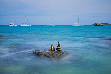 Scenic view of sea with stacked rocks against cloudy sky