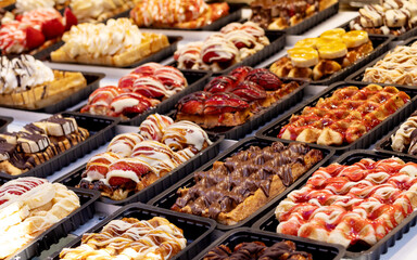 Traditional Belgian waffles decorated with fruit and cream lie in a row on the table close-up