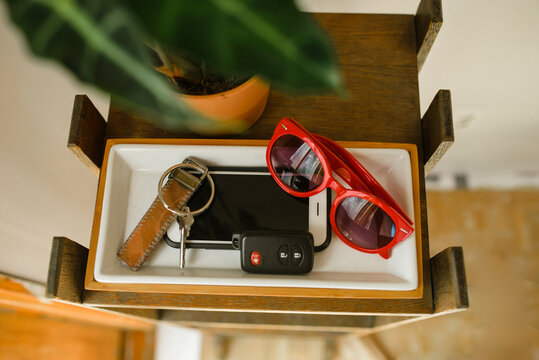Close-up of sunglasses, smart phone and keys in tray by potted plant on table at home