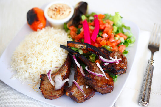 Close-up of lamb chops with salad and rice served in plate on table