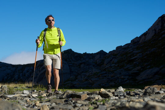 Surface level of man hiking on field against clear blue sky during sunny day