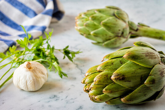 Artichokes, garlic and parsley on a marble counter