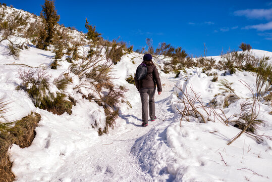 Rear view of woman walking on snow covered field against sky