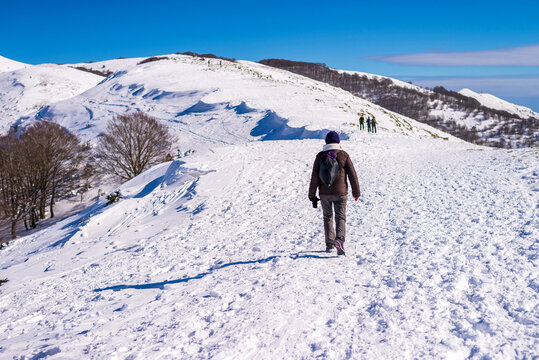 ear view of woman walking on snow covered field against sky