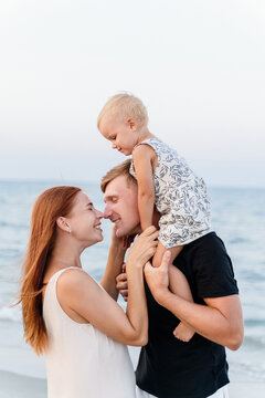 Side view of a happy family with a small child hugging on the beach