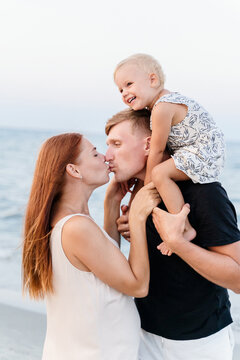 Side view of a happy family with a small child hugging on the beach