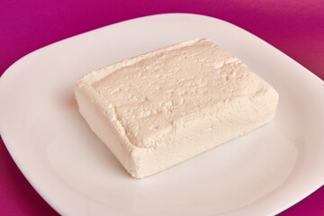 A slice of sour milk cheese on a white plate.