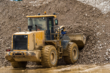 Fototapeta na wymiar Front end loader dumping stone and sand in a mining quarry