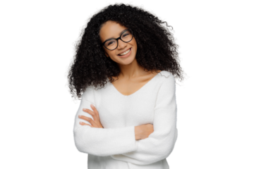 Half length shot of friendly looking African American woman tilts head, has dark crisp bushy hair, keeps arms folded over chest, wears casual white sweater, enjoys photoshoot in studio. Emotions