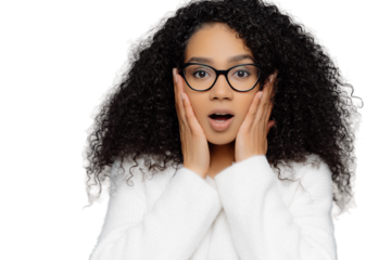 Close up portrait of shocked concerned young woman with dark skin and curly hair, hears terrifying news, keeps hands on cheeks, wears spectacles and white sweater, isolated on grey background