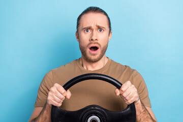 Photo of handsome worried man tail hairdo dressed beige t-shirt hold steering wheel got in accident isolated on blue color background - obrazy, fototapety, plakaty