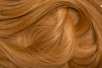 Red hair close-up as a background. Women's long orange hair. Beautifully styled wavy shiny curls....