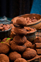 Sweet chocolate truffles with cocoa powder. On a dark chocolate background. Cocoa beans.