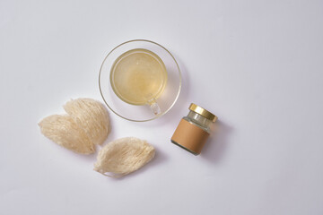A glass cup filled with bird’s nest soup, edible bird’s nest and an empty label jar for product mockup. Bird’s nest is precious and rare medicine, with several beneficial nutrients