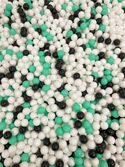 Many beads of different color white black green as background