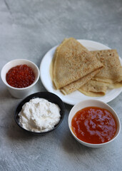 Tiny crepes on a plate. Crepes with salmon caviar. Savory food close up photo. Traditional French pancakes. 