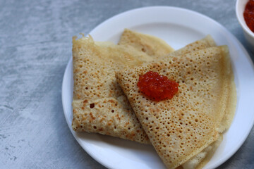 Tiny crepes on a plate. Crepes with salmon caviar. Savory food close up photo. Traditional French pancakes. 