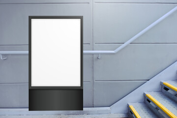 Blank white vertical digital display in front of painted concrete wall, beside flight of stairs....