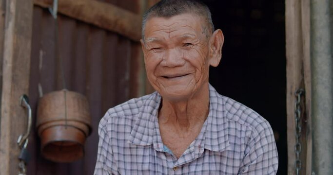 An Asian man who is more than seventy years old and works as a wage earner in a farm, live in an old house, smiling and laughing happily. 