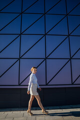 a woman walks near the glass wall of a building walk on the street