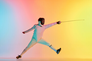 Fototapeta na wymiar Long attack. Young man, male fencer with sword practicing in fencing over gradient pink-yellow background in neon light. Sportsman shows fencing technique
