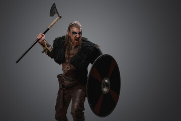 Fototapeta na wymiar Portrait of violent barbarian from north with deerskin and armor against gray background.