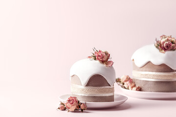Glazed Easter cakes decorated with dry tea rose flowers on pastel pink background. Holiday background with copy space for your design.