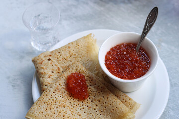 Tiny crepes on a plate. Crepes with salmon caviar. Savory food close up photo. Traditional French pancakes. 