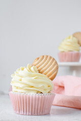 Pink cupcakes with tall american buttercream swirl and cookie garnish, cupcakes in pink liners with a tall vanilla buttercream and a cookie, birthday cupcakes on a white background