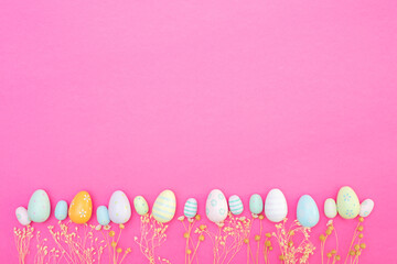 Happy Easter. Banner or greeting card background with easter eggs and dry flowers. Composition with Easter eggs and pink background. Flat lay, top view, copy space.