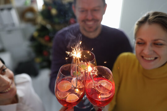 Cheerful happy people hold alcoholic cocktails with sparklers closeup - Powered by Adobe