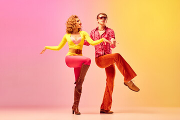 Disco style. Young emotional man and woman, professional dancers in retro clothes dancing dance over pink-yellow background. 1970s, 1980s fashion, music concept