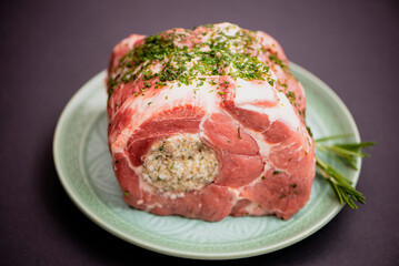 raw pork meat stuffed with sauce for cooking in the oven on a dark background
