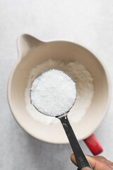 Fototapeta na wymiar White sugar in a measuring cup, sugar for baking in a cup