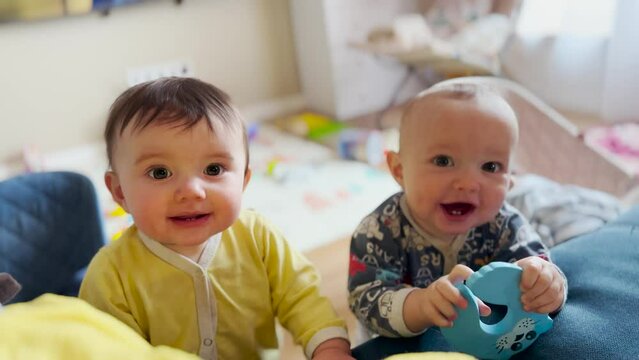 Twin baby connection. children baby have fun with toys on the sofa. Cute moments, the twins baby play in the room on the couch. Double naughty: twins baby play and laugh on fun the couch